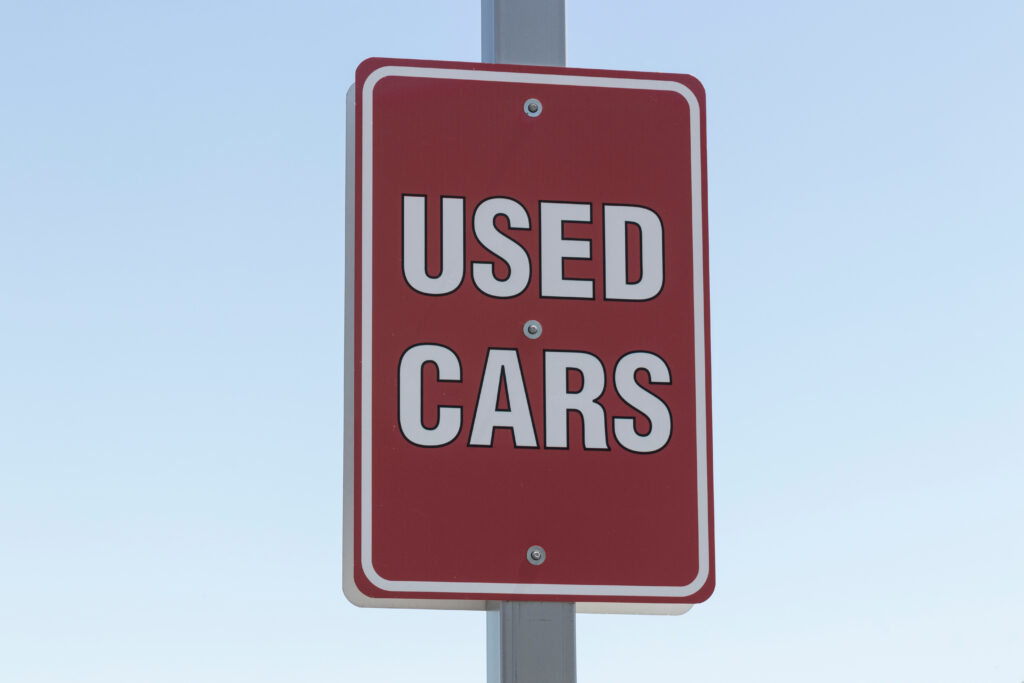 Used car sign at a pre-owned auto dealership. With supply issues, used and preowned cars are in high demand.